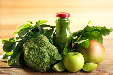 Green healthy juice with fruits and vegetables on wooden background