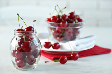 Cherries in glass bowl on table, on light background