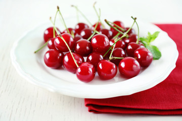 Sweet cherries on plate, on light background