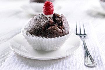 Delicious chocolate cupcake with raspberry on table close up