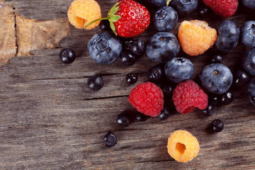 Heap of sweet tasty berries on wooden table close up