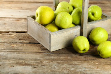 Ripe green apple in crate on wooden table close up