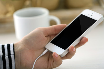 Music smartphone in female hand, on light background