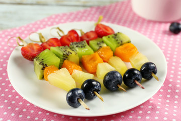 Fresh fruits on skewers in plate on napkin, closeup