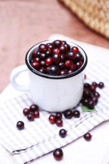 Red gooseberry in cup on wooden table close-up outdoors