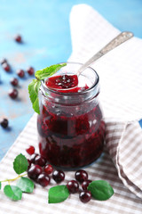 Jar of gooseberry jam on wooden table close-up