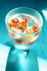 Glass of cold refreshing summer drink with berries and ice cubes on table close up
