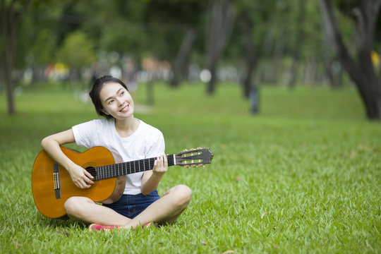 Young attractive woman playing acoustic guitar