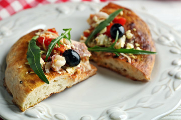 Pieces of homemade pizza on plate, on color table background
