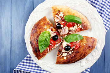 Pieces of homemade pizza on plate, on color table background