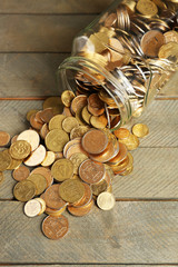 Glass jar with coins on wooden background