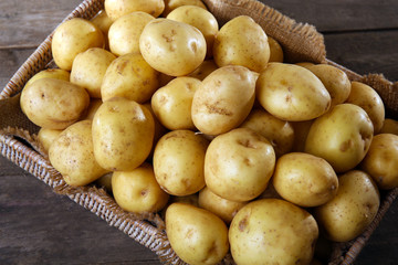 New potatoes in tray on wooden table, closeup