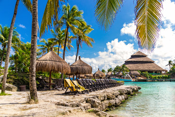 Relax in Mexico. Tropical paradise beach with sun beds under the palm trees in Xcaret park