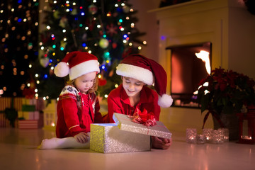 Fototapeta na wymiar Kids opening Christmas presents at fireplace