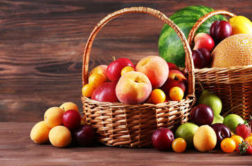 Assorted of fresh fruits in wicker baskets on wooden background