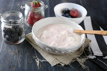 Delicious vanilla ice cream in bowl and frozen berries, on wooden background