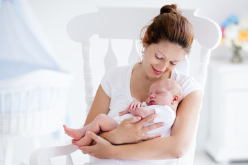 Young mother and newborn baby in white bedroom