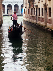 Gondolier ferrying tourists with its gondola in Venice, near the Grand Canal.