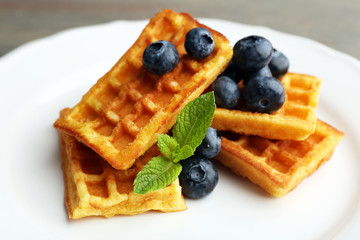 Sweet homemade waffles with forest berries and chocolate sauce on table background