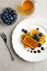 Sweet homemade waffles with forest berries and chocolate sauce on table background