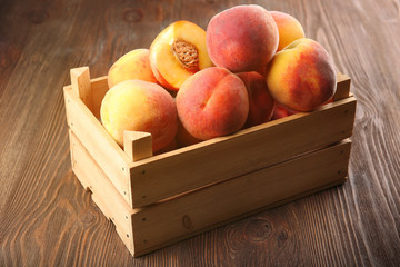 Fresh peaches in crate on wooden background