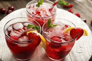 Glasses of berry juice on wooden table, closeup