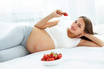 Obraz na płótnie Canvas Pregnant Woman Eating Strawberry at home. Healthy Food Concept. Healthy Lifestyle. Diet