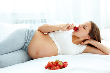 Pregnant Woman Eating Strawberry at home. Healthy Food Concept. Healthy Lifestyle. Diet