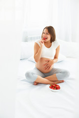 Pregnant Woman Eating Strawberry at home. Healthy Food Concept.