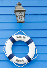 Life buoy welcome aboard sign and old lamp