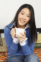 A smiling woman with a coffee or tea cup.