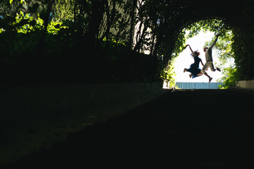  couple jumping in the end of tunnel with trees