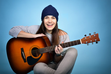 young woman playing music on acoustic guitar