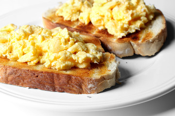 Scrambled egg on toast.
Scrambled egg on toast on a plate.
