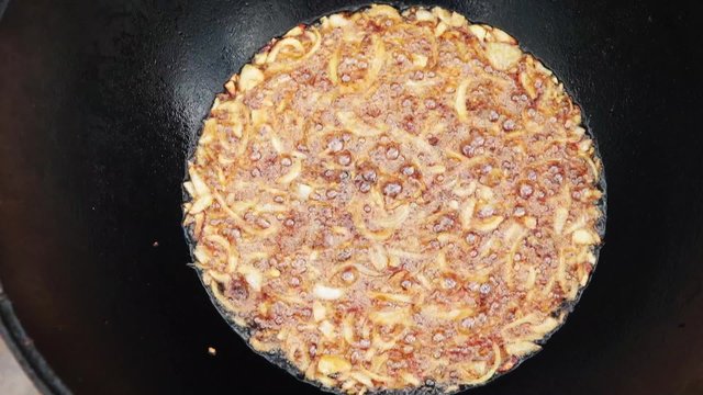 Uzbek national dish pilaf in a large cast-iron cauldron on the fire, fry the chopped onion until golden brown, lamb, carrot, mutton fat, the fat tail, sesame oil, garlic