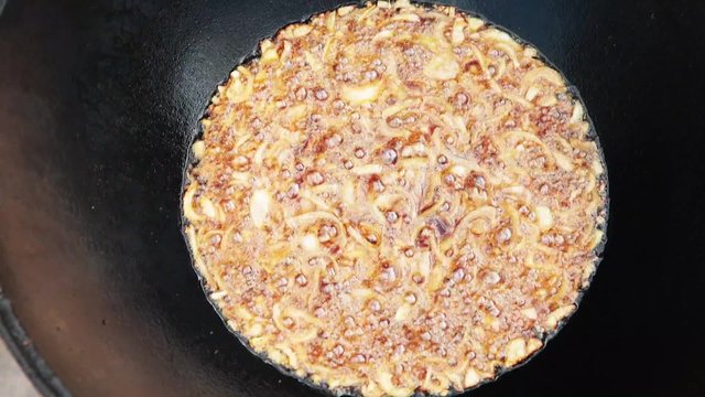 Uzbek national dish pilaf in a large cast-iron cauldron on the fire, fry the chopped onion until golden brown, lamb, carrot, mutton fat, the fat tail, sesame oil, garlic