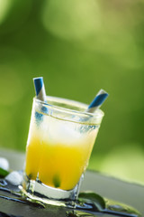 Screwdriver cocktail with ice on a blurred green background, sel