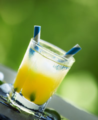 Screwdriver cocktail with ice on a blurred green background, sel