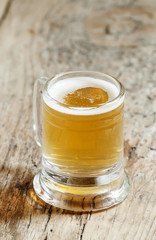 light beer in a little old-fashioned mug on old wooden table, se