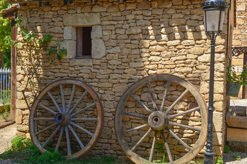 Fototapeta na wymiar 2 roues en bois contre mur en pierres