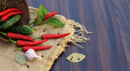 red pepper with leaves on sacking on the table with a basket