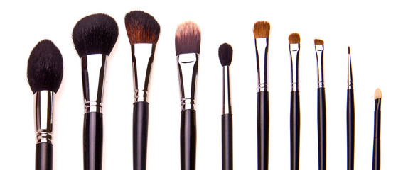 Set of essential professional make-up brushes, isolated with shadows on white background. Overhead view. Front part. Place for your text.