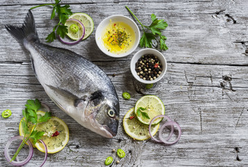fresh Dorado fish, lemon, lime and parsley on a light wooden surface