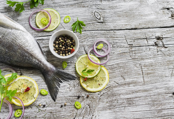 fresh Dorado fish, lemon, lime and parsley on a light wooden surface
