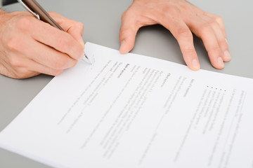 close-up shot of hands signing a contract on desk in office