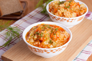 tomato soup with rice and vegetables in a white saucepan and bre