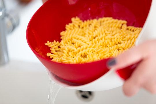 Fair-skinned hands dripping a portion of pasta for two people