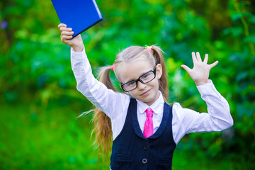 Fototapeta na wymiar Adorable little school girl with book outdoor. Back to school 