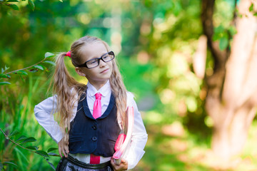Fototapeta na wymiar Portrait of adorable little school girl with notes in glasses