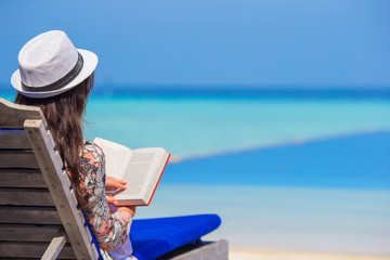 Young woman reading book during tropical white beach